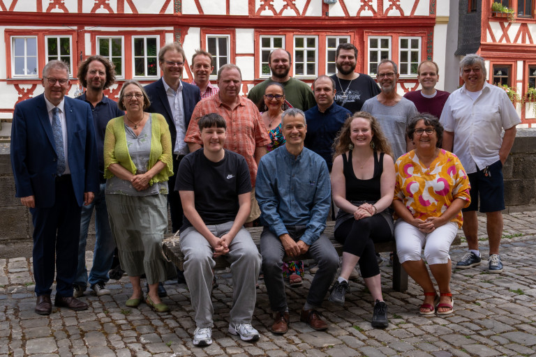 Die Kandidatinnen und Kandidaten von SPD und Ochsenfurter Liste sitzen auf einer Bank vor der Fachwerkzeile in der Ochsenfurter Altstadt.